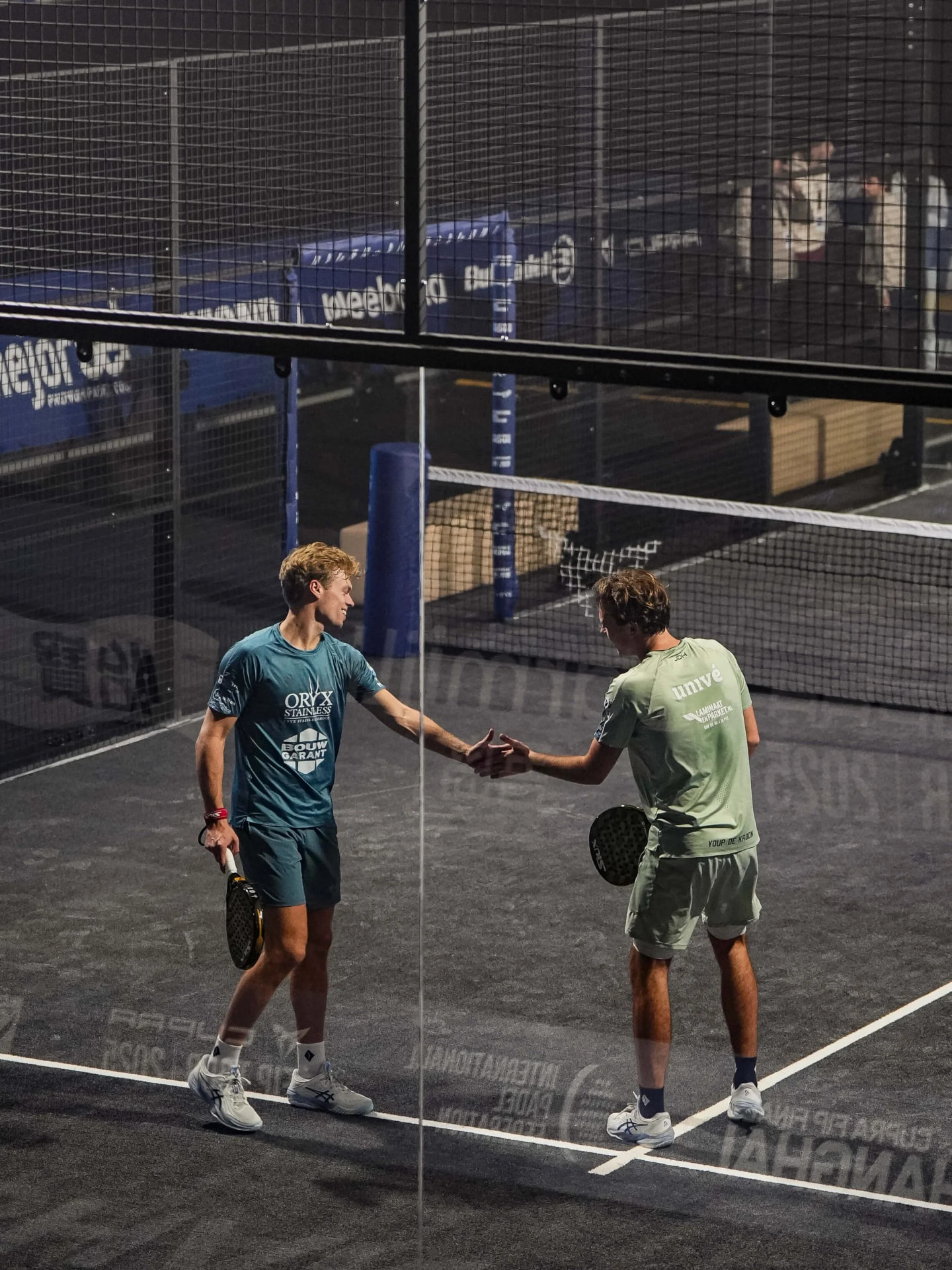 Due giocatori si stringono la mano a fine partita su un campo da padel
