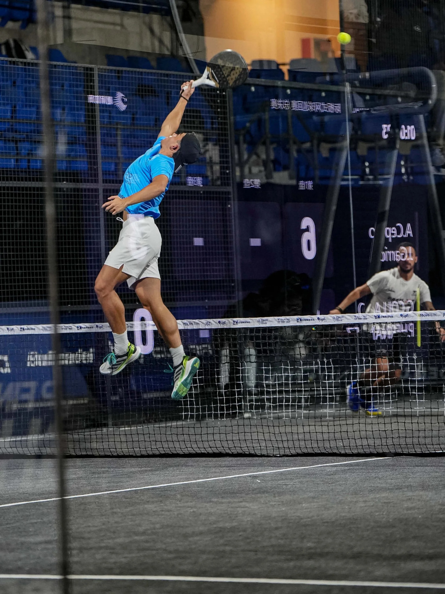 Giocatore di padel a rete colpisce in salto durante un match notturno